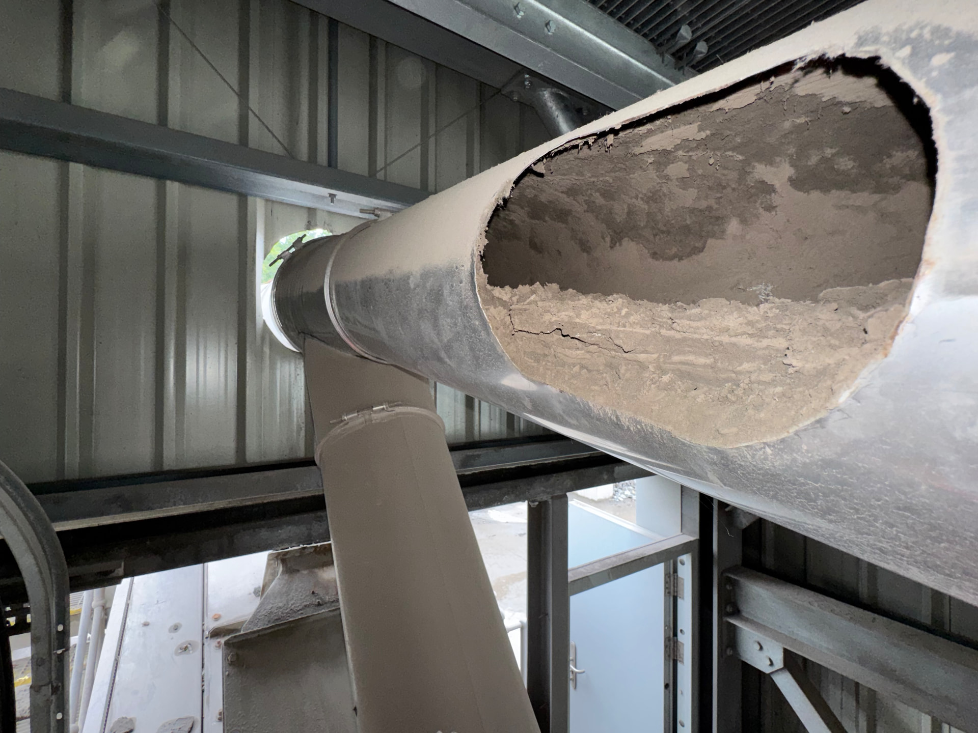 Cut section of industrial extract ductwork showing heavy compacted dust deposit