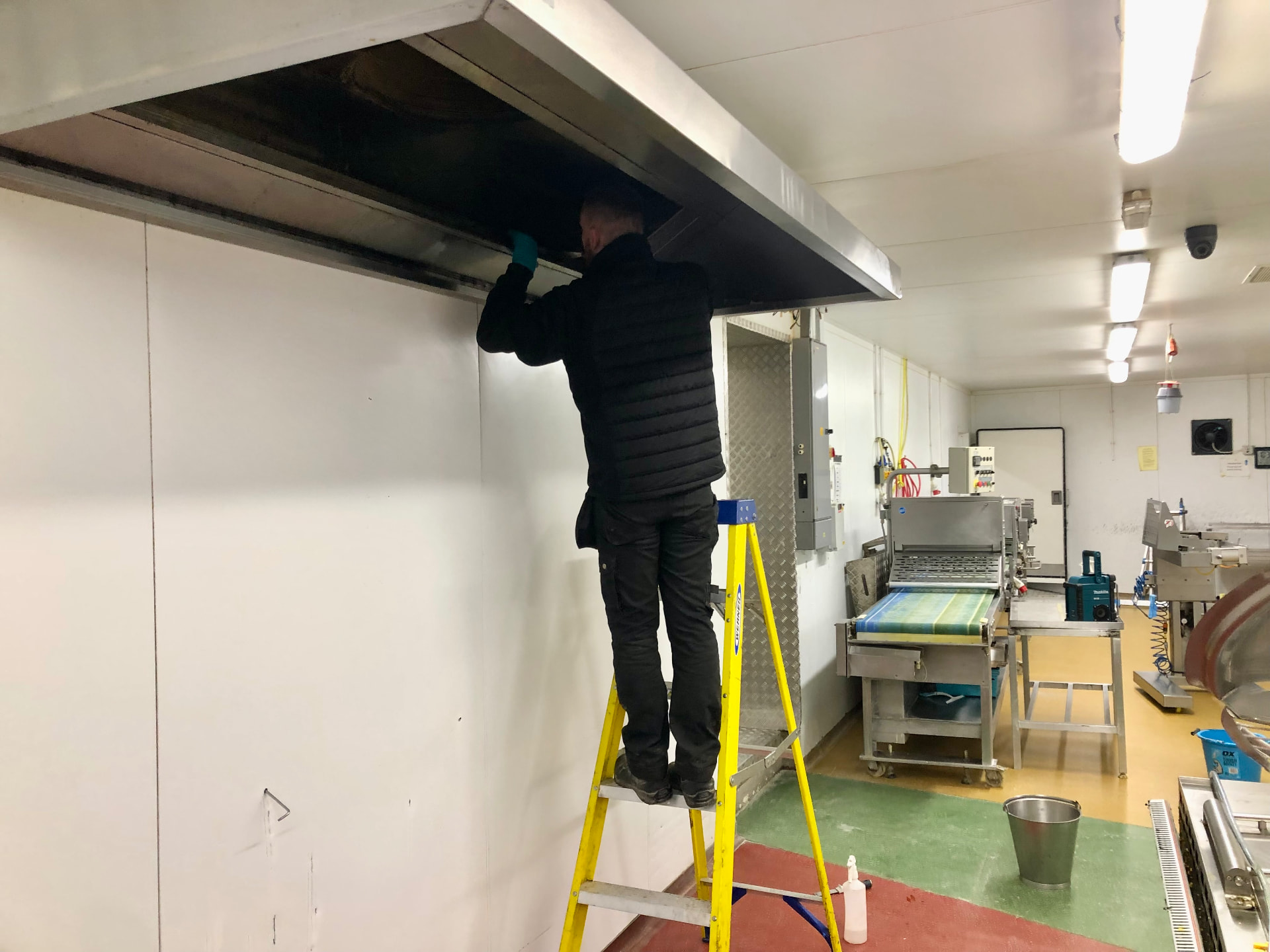 Engineer cleaning a commercial kitchen extract canopy